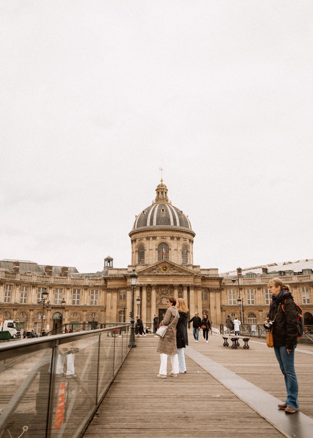People on a bridge looking at the Institut de France.
